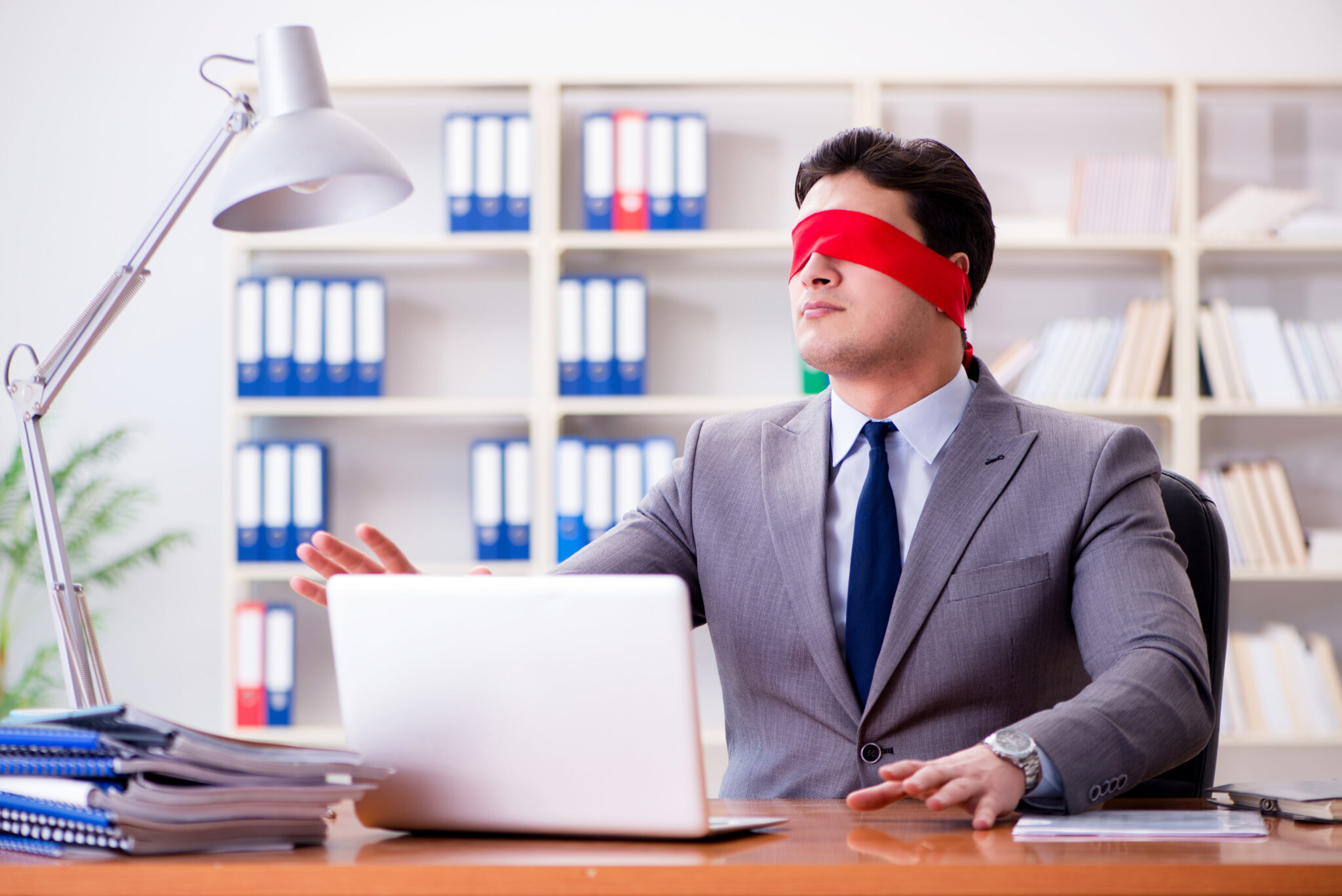 Blindfold businessman sitting at desk in office